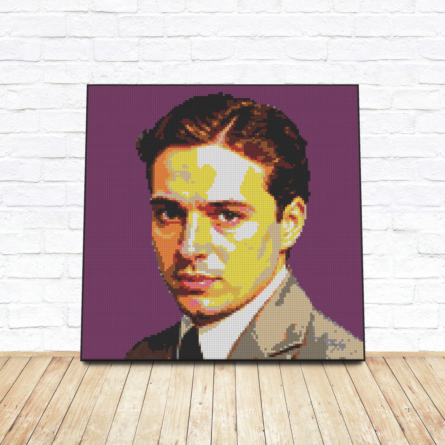 Framed LEGO tile pop-art portrait of Charlie Chaplin leaning against a white brick wall