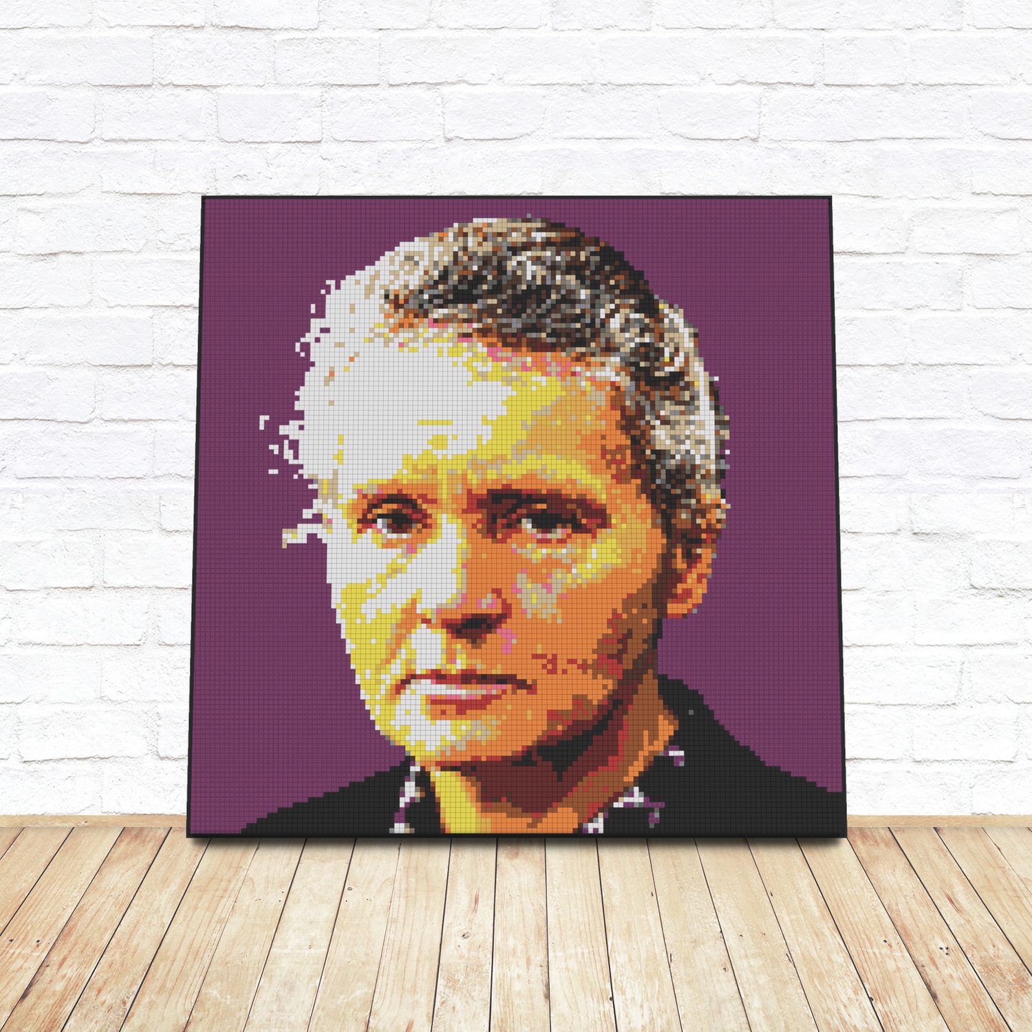 Framed LEGO tile pop-art portrait of Marie Curie leaning against a white brick wall